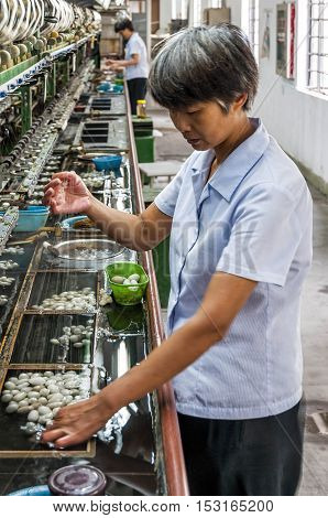 Suzhou, China - August 12, 2011: View of a silk thread maker in the Suzhou No.1 Silk Mill factory. Silk is a natural fiber, some forms of which can be woven into textiles. Is obtained from the cocoons