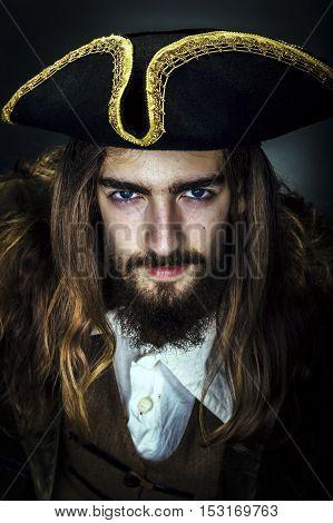 Portrait of a medieval bearded pirate on black background.