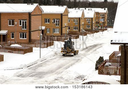 excavator cleans snow road in the cottage winter