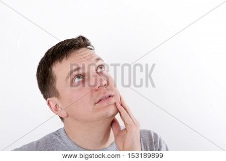 Thinking man isolated on white background. Closeup portrait of a casual young pensive man looking up at copyspace. Caucasian male model.