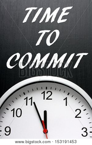 The words Time To Commit on a blackboard above a clock as a call to action when making decisions