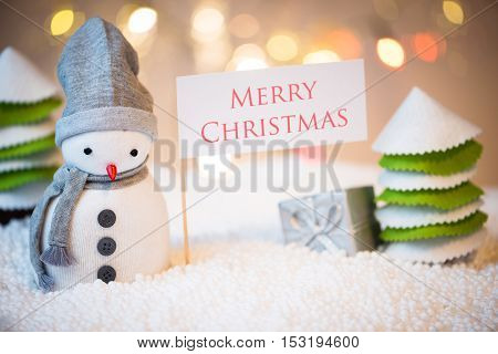 Cute festive snowman with Merry Christmas sign Christmas lights in background