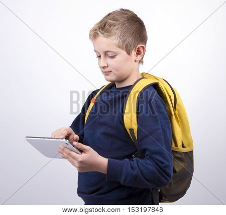 boy teenager with a backpack looking to the plate in portrait. Dressed in jeans and a blue sweater yellow backpack education concept