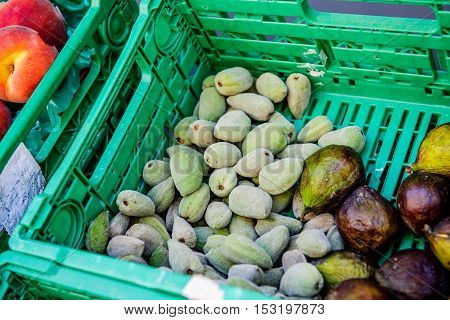 Fresh green almonds with shell in a market next to fig fruits in the iconic Marche de la Place Richelme.
