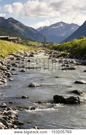 Spol River With Church Of Santa Maria In Livigno, Italy