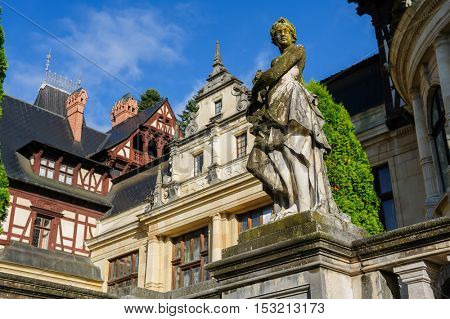Statue in front of beautiful Peles castle and ornamental garden in Sinaia, Romania, between Valachia and Transylvania