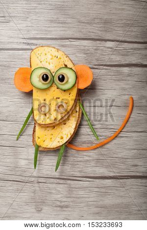 Monkey made of bread and vegetables on wooden background