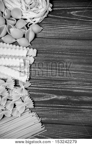 Pasta mix on dark wooden table background. Black and white