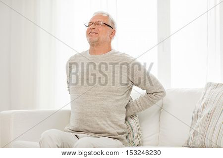 people, healthcare and problem concept - unhappy senior man suffering from pain in back or reins at home