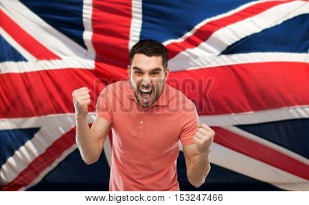 emotion, aggression, patriotism, gesture and people concept - angry young man showing fists and shouting over brittish flag