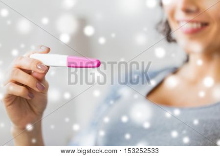 pregnancy, fertility, maternity and people concept - close up of happy smiling woman with home pregnancy test over snow