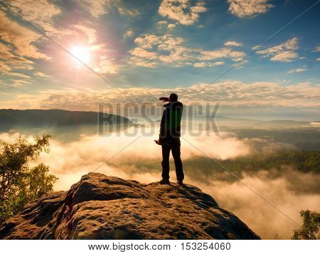 Professional Photographer With Tripod On Cliff And Thinking. Dreamy Fog