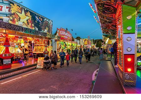 ALBA, ITALY - OCTOBER 10, 2015: People walking by illuminated attractions at Luna Park - traditional amusement park taking place each year on october during International White Truffle Festival.