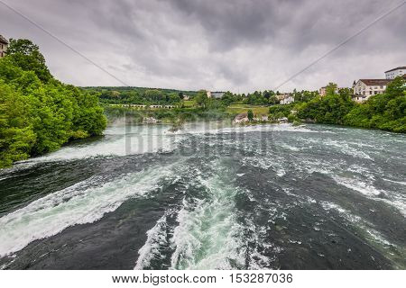 Rhine Falls in cloudy weather in Neuhausen am Rheinfall Schaffhausen Switzerland. The Rhine Falls is the largest waterfall in Europe.