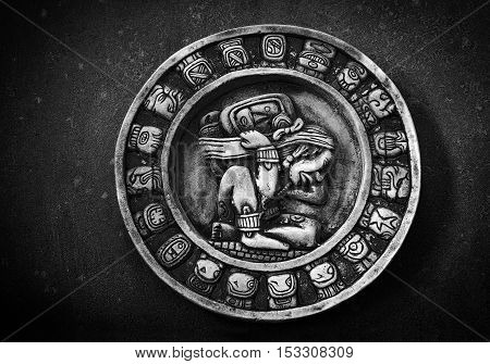 Carved circular Mayan calendar on textured background