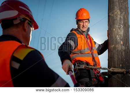 RUSSIA - OCTOBER, 2016: Electrician lineman repairman worker at climbing work on electric post power pole