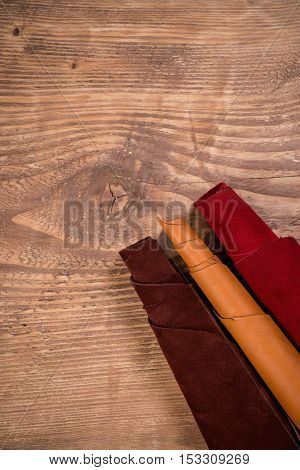 Brownorange and red leather in rolls on the wooden background. Leather craft. Copy space.