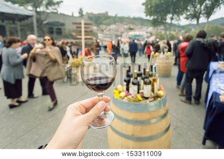 Glass of wine at tasting area of annual city festival Tbilisoba with crowd of people around. Tbilisi, the capital of Georgia country