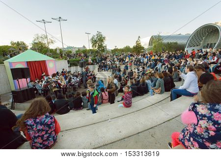 TBILISI, GEORGIA - OCT 15, 2016: Crowd of young people sitting on a concert of an orchestra at park Rike during festival Tbilisoba on October 15, 2016. Tbilisoba is traditional festival in Tbilisi from 1979