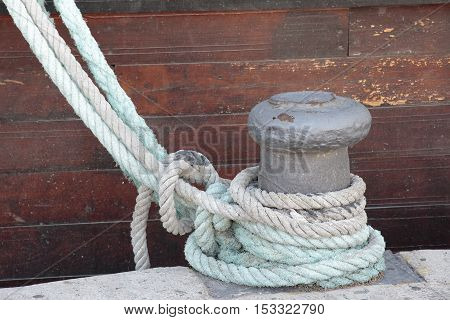 foreground of ropes of a boat tied on a bollard