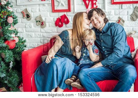 Family In Christmas Decorations On A Red Couch