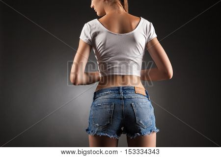 Sexy butt in denim shorts. Studio portrait black background.