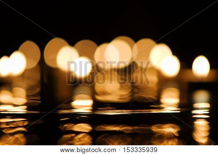 Christmas or festive concept: defocused candlelight with reflection in darkness