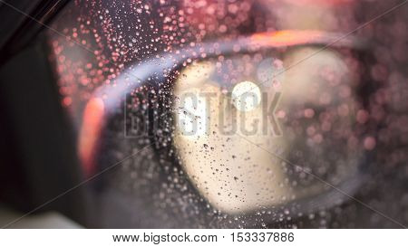 Blurred droplets and car lights reflections through foggy car window
