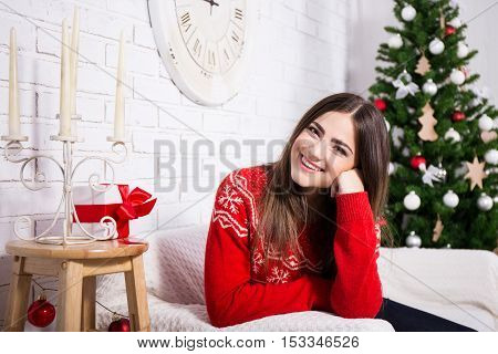 Happy Young Woman Daydreming In Decorated Living Room With Christmas Tree