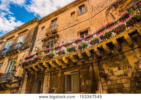 Baroque facede decorated with flowers in Italy. Beautiful travel photo. Colorful background texture with architecture and flowers.