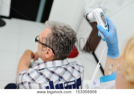 baldness. diagnostics hair and scalp. Trihoskopiya. Doctor examine patient male hair a special apparatus.