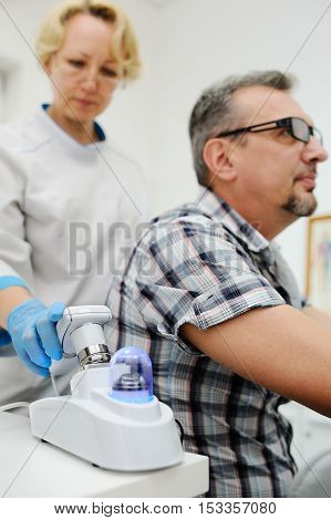 baldness. diagnostics hair and scalp. Trihoskopiya. Doctor examine patient male hair a special apparatus.