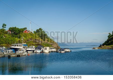 House on the hill and small motor boats docked at pier. Falkensten, Norway.