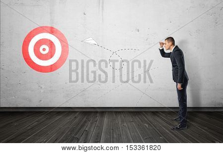 Businessman keeping track of the paper airplane flying right on target. Long-term plan. Distant goal. Total control.
