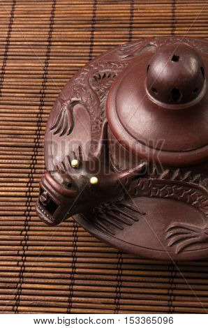 brown Chinese teapot of Yixing clay with traditional ornament on bamboo Mat