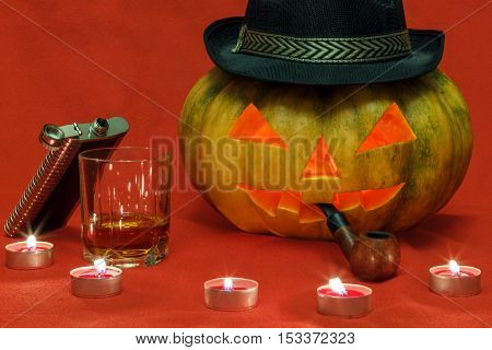 Pumpkin for Halloween with glowing eyes, smoking pipe and glass of whiskey