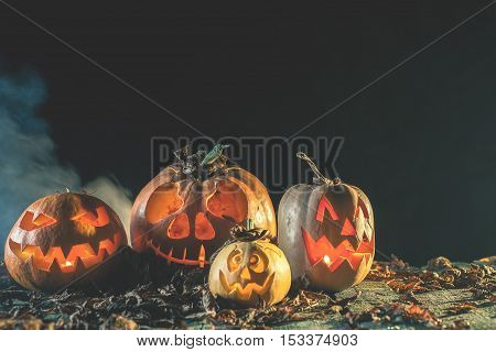 Halloween pumpkins at wood background. Carved scary faces of pumpkin. Night horror. October holiday. Pumpkin family