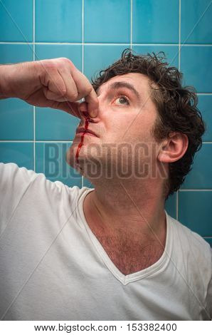 Curly haired man in bathroom with bad nose bleed