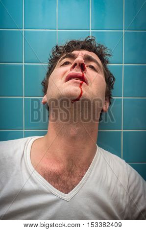Curly haired man in bathroom with bad nose bleed