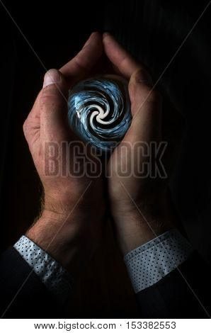 Hands holding magic crystal ball with smoky hypnosis spiral