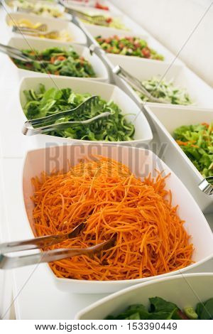 Close-up, soft focus salad bar with a variety of fresh vegetables. Colorful organic raw slice of lettuce, carrots, rukula, cucumber and pecans. Healthy eating food. (selective focus)