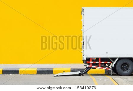 Delivery truck parking at footpath with yellow wall background and space for text