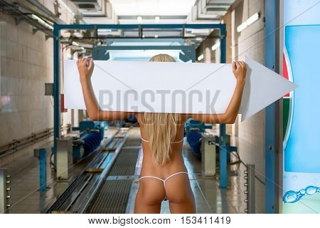 Back view of sexy blonde holds pointer to car wash