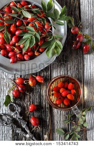 Rosehip tea in glass cup and berries on vintage plate top view