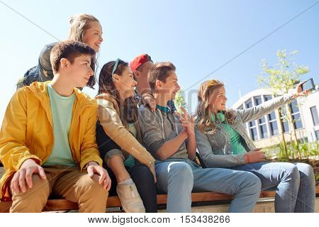 education, high school, technology and people concept - group of happy teenage students or friends taking selfie by smartphone