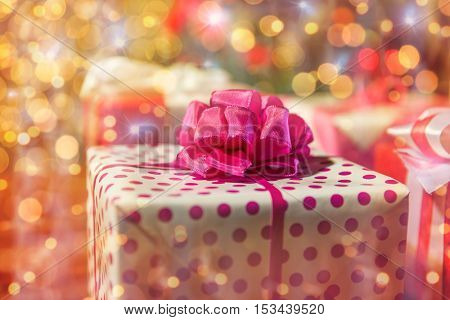christmas, holidays, presents, new year and celebration concept - close up of gift boxes over christmas tree lights