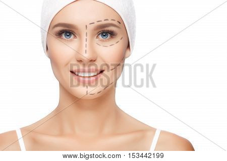 Young woman with perforation lines on her face before plastic surgery operation. Beautician touch and draw correction lines on woman face. Isolated
