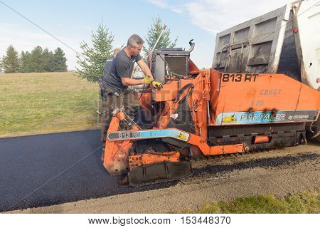 Colbert, WA - October 24, 2016: Workers from Black Diamond Asphalt Paving, LLC., repairing patches and re-paving a private road/driveway