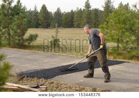Colbert, WA - October 24, 2016: Workers of Black Diamond Asphalt Paving, LLC., repairing patches in a private road/driveway