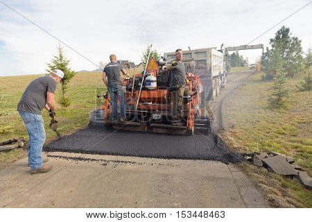 Colbert, WA - October 24, 2016: Workers from Black Diamond Asphalt Paving, LLC., repairing patches and re-paving a private road/driveway